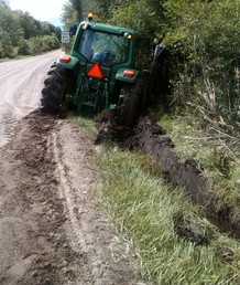 JD Stuck On Roadside - Got too close to the edge of the road with the  county mower tractor I operate while mowing   back some brush. Tandem county truck pulled me  out.