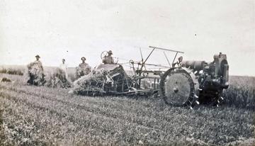 Moline Tractor - 2 Wheel Design - 1922? - This photo is from Dodge Center, MN on the Elton Delzer farm. We think this photo was taken in about 1934, and we think this is a 1922 model tractor made by the Moline Implement Company.  The man pictured driving the tractor is on the grain binder, operating the tractor from the binder seat, via a long shaft that controls the front two wheel tractor. If anyone knows the exact identification and year of the tractor,  please let us know
